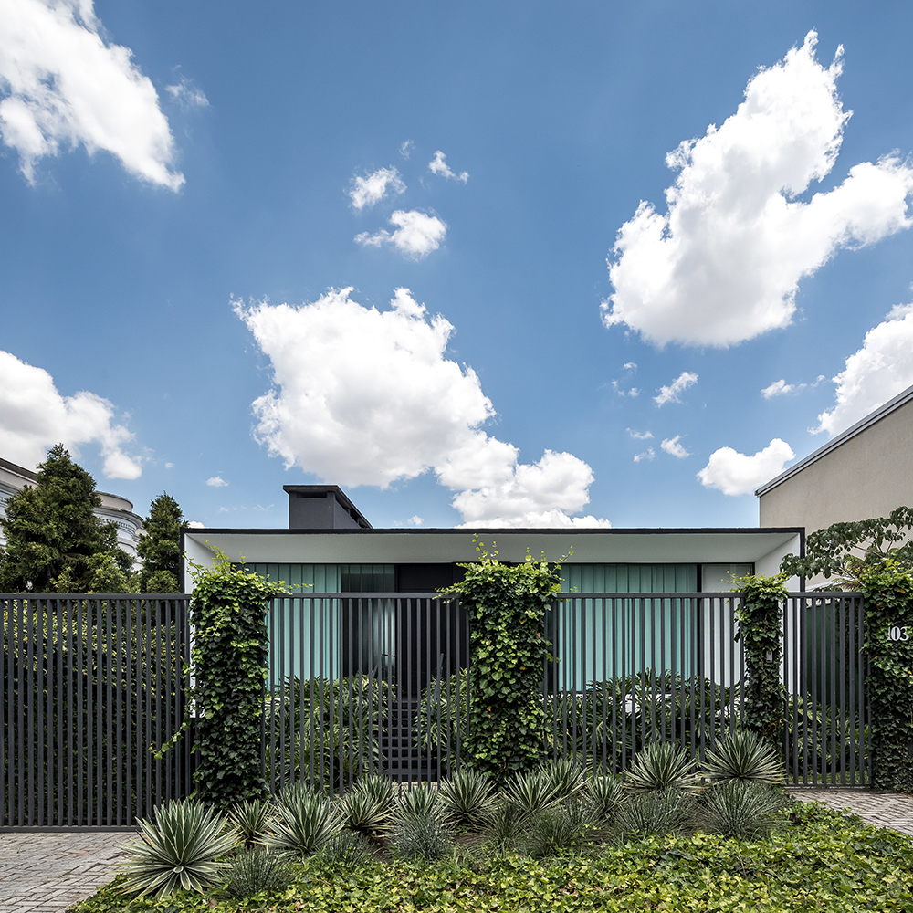 Uma casa moderna com cerca e arbustos.