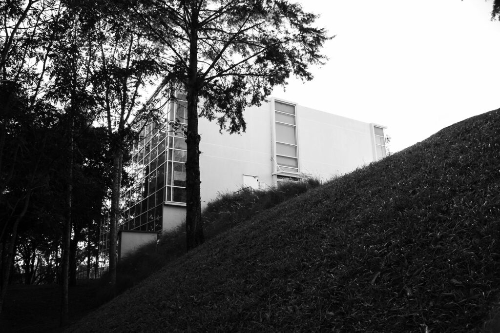 Fotografia preto branco vista lateral projeto arquitetônico laboratorio em cima de colina com arvores